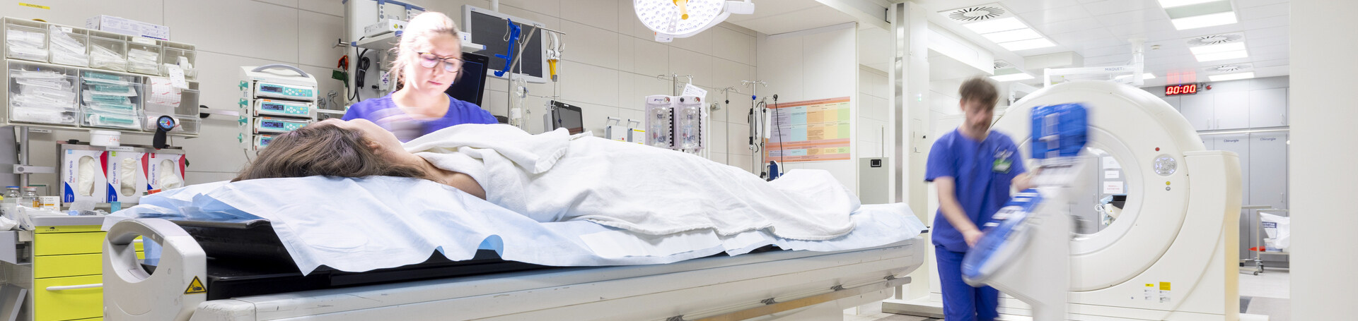 MTR bereitet Patientin auf Behandlung vor und zweiter MTR bereitet Behandlungsraum vor
